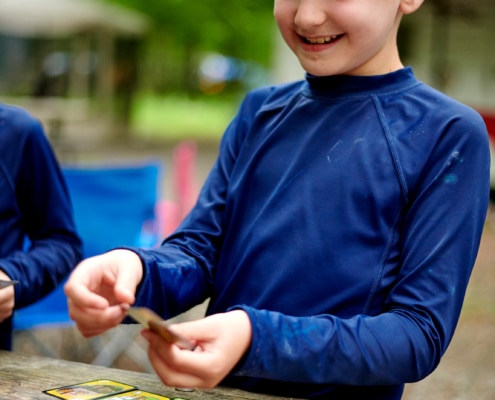 boys play cards at campsite