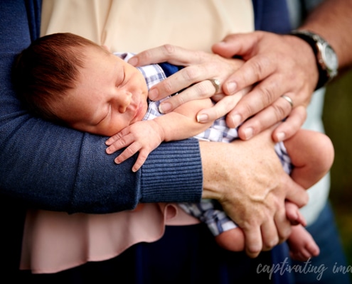 closeup of sleeping baby with parents' hands